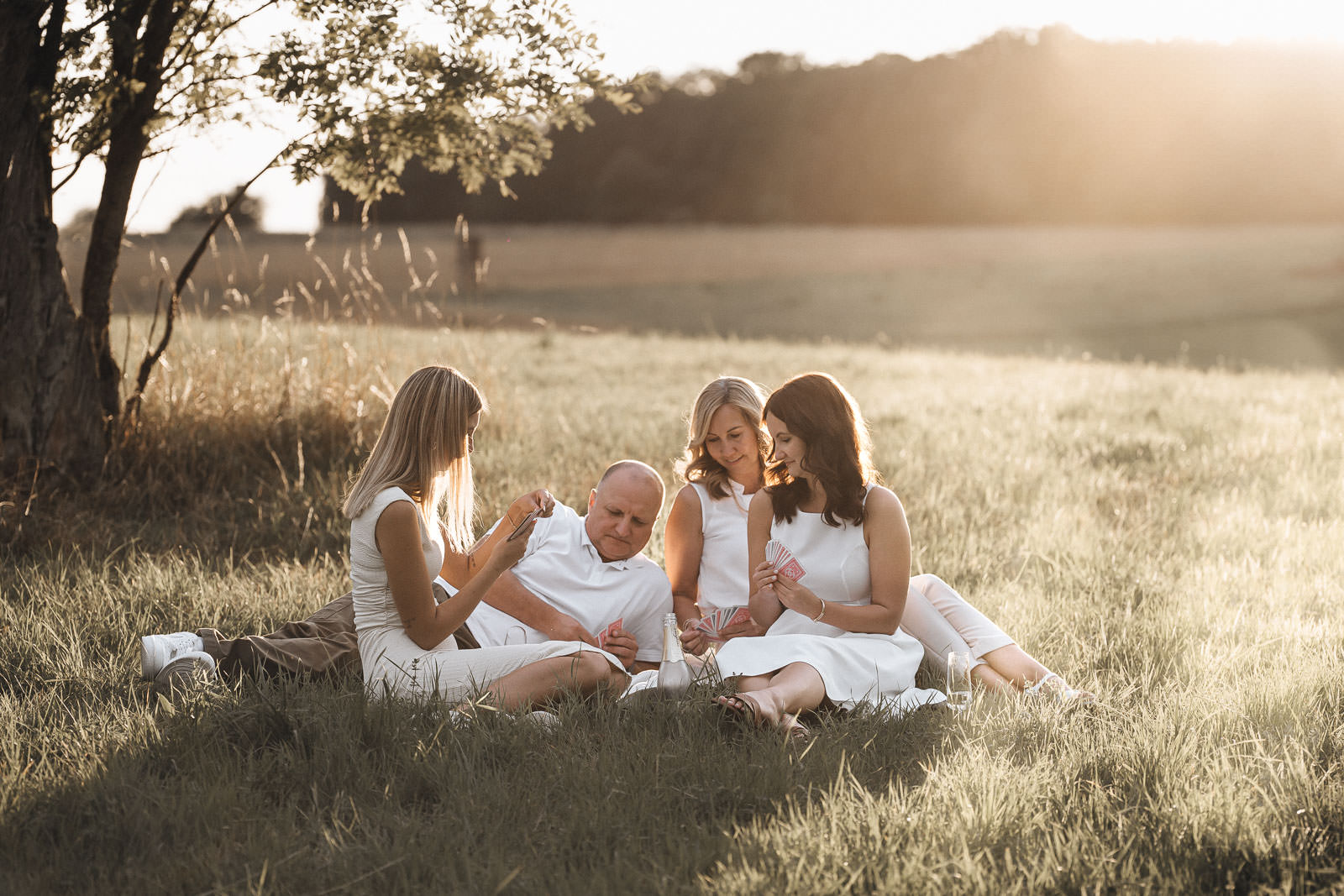 Familie spielt gemeinsam Karten im Sonnenuntergang bei einem entspannten Outdoor-Shooting